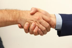 Manos en saludo simbolizando la misión de Montiglio y Asociados Abogados de ser reconocidos como profesionales cercanos y humanos, brindando confianza y comprensión a micro, pequeñas y medianas empresas para construir relaciones sólidas y duraderas